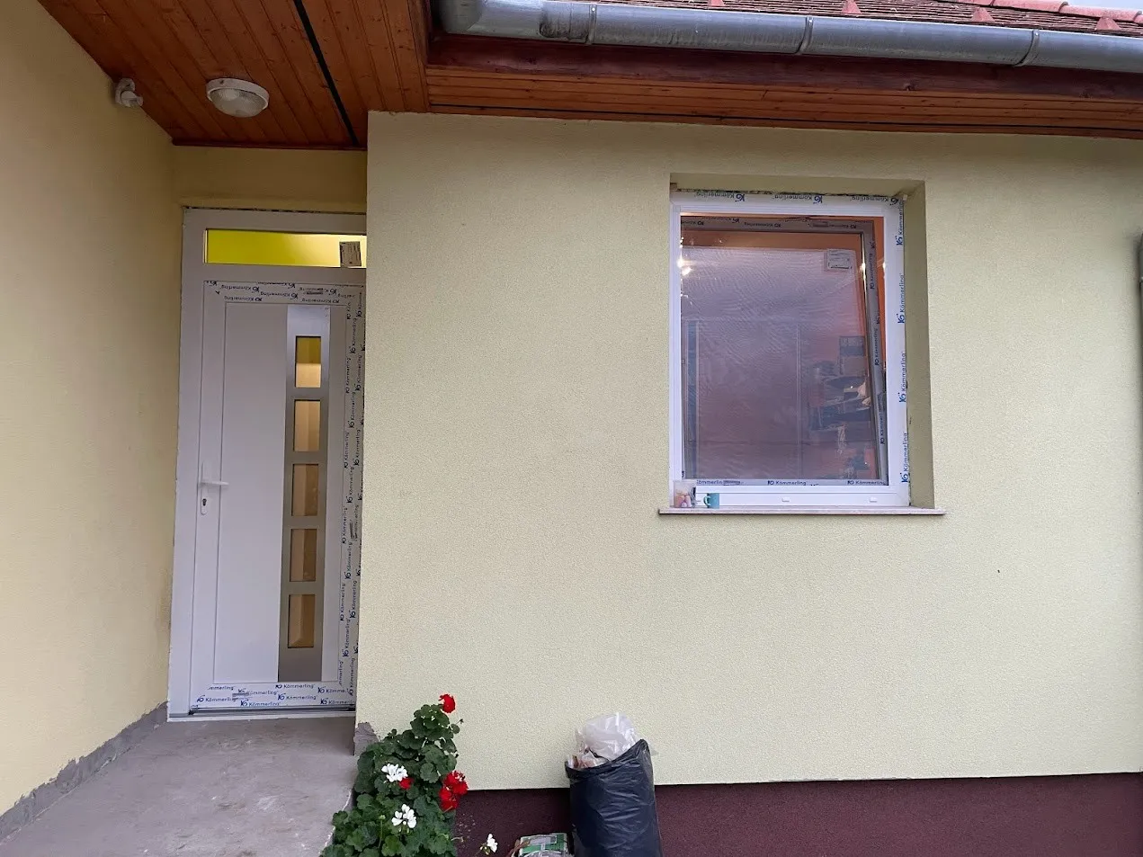 Utána: Új bejárati ajtó és ablak egy családi ház bejáratánál.
